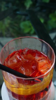 Yeşil arka planda Negroni kokteyli yakın plan. Dikey