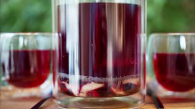 Terasta bir masada iki bardak meyve çaydanlığı ile bir infuser çaydanlığını kapat