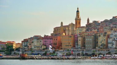 Denizde yüzen insanlar, Fransa 'nın Menton kentindeki renkli binaları görüyorlar.