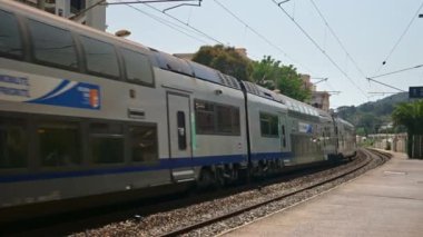 Antibes, Fransa - 20 Temmuz 2024: Gri ve mavi, uzun tren istasyondan yavaşça geçiyor