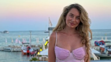 Cannes, Fransa 'da akşam vakti plajda pembe elbiseli bir kadın poz veriyor.