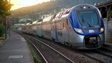 Antibes, Fransa - 20 Temmuz 2024: Gri ve mavi, uzun tren istasyondan yavaşça geçiyor