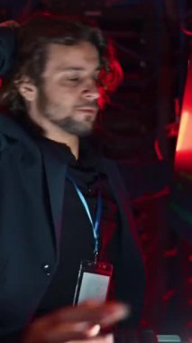 Sunucu odasında yanıp sönen kırmızı ışıklarla hatayı düzeltmeye çalışan bir adam ve bir kadın. Dikey