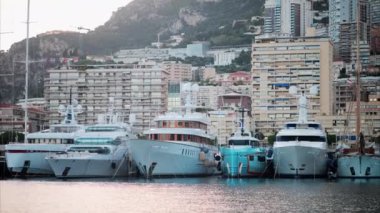 Monaco Marina 'ya kenetlenmiş teknelerin görüntüsü ve arka planda şehrin silüeti.