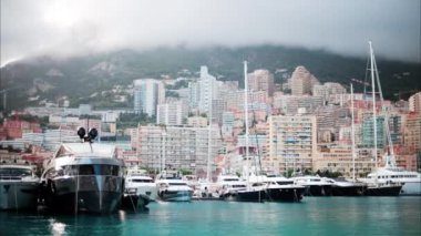 Monaco Marina 'ya kenetlenmiş teknelerin görüntüsü ve arka planda şehrin silüeti.