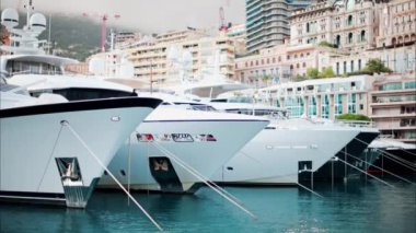 Monaco Marina 'ya kenetlenmiş teknelerin görüntüsü ve arka planda şehrin silüeti.