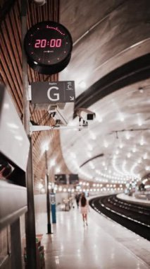 Parlak ışıklarla Monako tren istasyonunda hareket eden insanların bulanık görüntüsü. Dikey