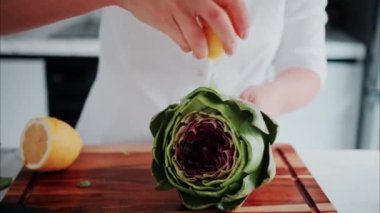 Tahta kesme tahtasının üzerinde limon suyu sıkan bir kadın.