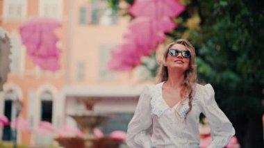 Fransa 'nın Grasse kentinin caddelerinde pembe şemsiye sıralarının altında yürüyen bir kadın.