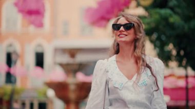 Fransa 'nın Grasse kentinin caddelerinde pembe şemsiye sıralarının altında yürüyen bir kadın.