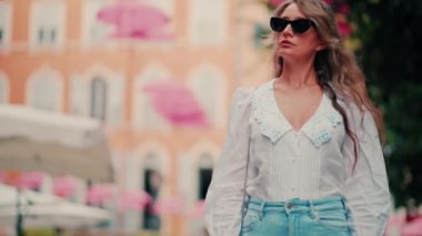 Fransa 'nın Grasse kentinin caddelerinin üzerindeki pembe şemsiye sıralarının altına bakan bir kadın.