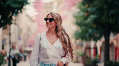 Fransa 'nın Grasse kentinin caddelerinde pembe şemsiye sıralarının altında yürüyen bir kadın.