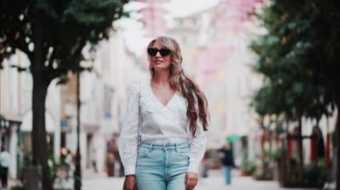 Fransa 'nın Grasse kentinin caddelerinde pembe şemsiye sıralarının altında yürüyen bir kadın.