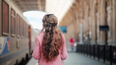 Pembe ceketli bir kadın Fransa 'daki Nice tren istasyonunda yürüyor.