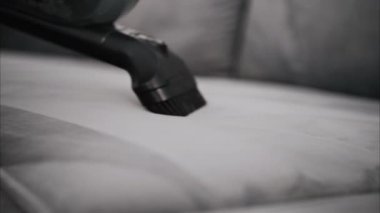 Gri bir kanepeyi temizleyen küçük bir süpürgeyi kapat.