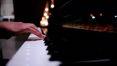 Arka planda bulanık ışıklarla piyano çalan bir kadının ellerini kapatın.