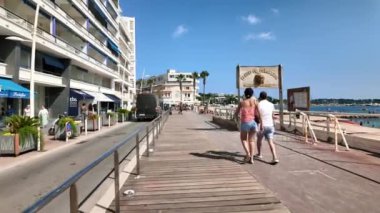 Juan-les-Pins, Fransa - 14 Ağustos 2024: Güneşli bir günde insanlar sahile yakın yürüyor