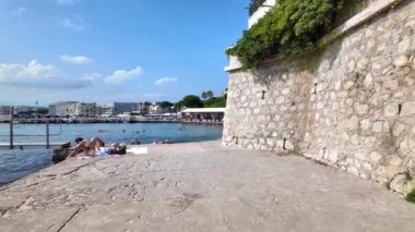 Juan-les-Pins, Fransa - 14 Ağustos 2024: İnsanlar denizde yüzüyor ve plajda dinleniyorlar