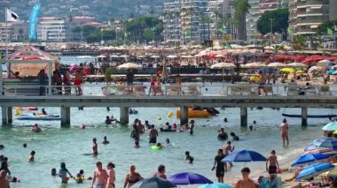 Juan-les-Pins, Fransa - 14 Ağustos 2024: İnsanlar denizde yüzüyor ve plajda dinleniyorlar