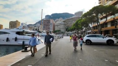 Monte Carlo, Monako - 4 Ekim 2024: Monaco Marina 'ya yanaşan çok sayıda beyaz teknenin yanında yürüyen insanlar