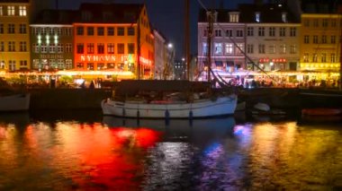 Kopenhag, Danimarka - 18 Ekim 2024: Nyhavn ilçesinin Gece Zamanlaması kanal suyunda renkli yansımalarla
