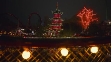 Geceleri Danimarka, Kopenhag 'daki Tivoli Bahçeleri' nde aydınlık bir tapınak manzarası ve çevre manzarası.