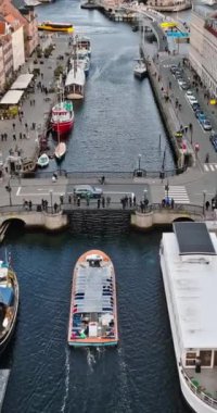 Danimarka 'nın Kopenhag kentindeki Nyhavn rıhtımındaki, kanal ve eğlence bölgesindeki teknelerin insansız hava aracı görüntüsü. Dikey