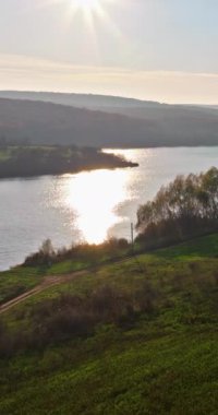 Moldova 'nın Orhei yakınlarındaki Raut nehrinin üzerinde parlayan güneşin insansız hava aracı görüntüsü. Dikey