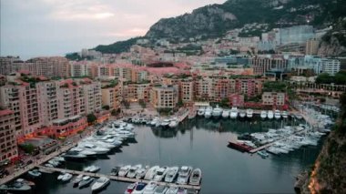 Port de Fontvieille 'e yanaşan teknelerin hava görüntüsü ve Monako' nun ufuk çizgisi akşam arkaplanda.