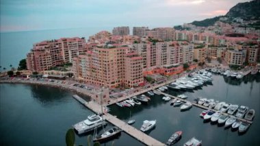 Port de Fontvieille 'e yanaşan teknelerin hava görüntüsü ve Monako' nun ufuk çizgisi akşam arkaplanda.