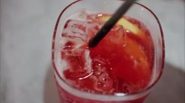 Kırmızı kokteyli siyah pipetle karıştıran bir kadının yakın çekimi.