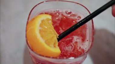 Kırmızı kokteyli siyah pipetle karıştıran bir kadının yakın çekimi.