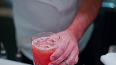 Barmen barda bir portakala kokteyl koyuyor.