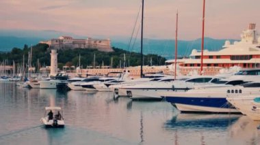 Fransa 'nın Antibes kentindeki Vauban Limanı' na yanaşmış birçok geminin yakınındaki bir teknede hareket eden insanlar.