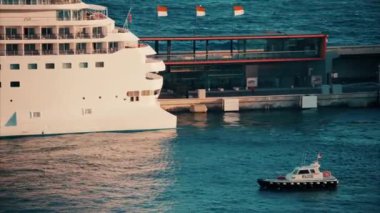Monte Carlo, Monaco - 14 Ekim 2024: Akşamleyin Monako Limanı 'na yanaşan büyük bir yolcu gemisinin yanında küçük bir tekne hareket ediyordu.