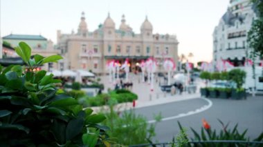 Monte Carlo Kumarhanesi 'nin önünde sallanan birden fazla Monegasque bayraklarının uzak, bulanık sokak görüntüsü