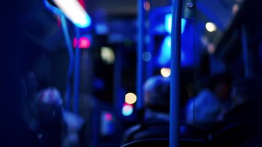 İnsanlar akşam hareket halindeki bir trende mavi ışıkla oturuyorlar.