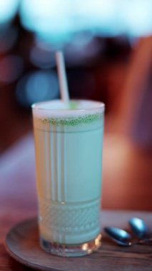 Kafedeki bir masada pipetle bardakta bir matcha latte 'yi kapat. Dikey