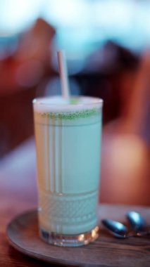 Kafedeki bir masada pipetle bardakta bir matcha latte 'yi kapat. Dikey