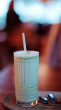 Kafedeki bir masada pipetle bardakta bir matcha latte 'yi kapat. Dikey