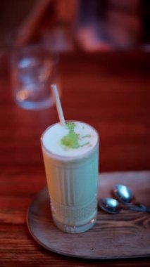 Kafedeki bir masada pipetle bardakta bir matcha latte 'yi kapat. Dikey