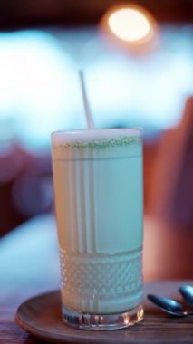 Kafedeki bir masada pipetle bardakta bir matcha latte 'yi kapat. Dikey