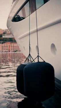 Monaco Marina 'ya yanaşmış arka planda binalar olan teknelerin yakın görüntüsü. Dikey