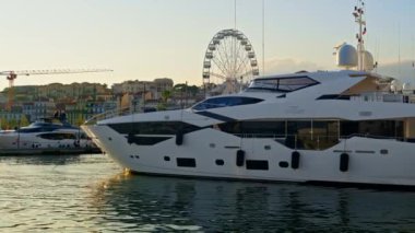 Cannes, Fransa - 15 Ekim 2024: Gemiler gün batımında Port de Cannes 'a yanaştı, arka planda dönen bir dönme dolap vardı.