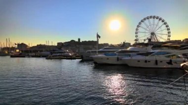 Cannes, Fransa - 15 Ekim 2024: Gemiler gün batımında Port de Cannes 'a yanaştı, arka planda dönen bir dönme dolap vardı.