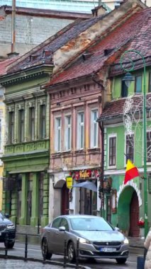 Brasov, Romanya - 20 Aralık 2024: Romanya 'nın eski Brasov kentinde yürüyen insanlar. Dikey