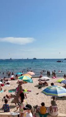 Cannes, Fransa - 15 Ekim 2024: İnsanlar sahilde yüzüyor ve dinleniyor. Dikey