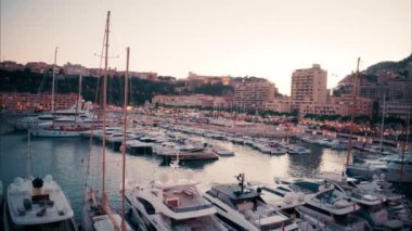 Monaco Marina 'ya yanaşan teknelerin görüntüsü ve arka planda şehrin silüeti var.