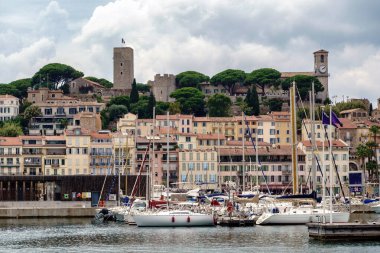 Cannes, Fransa 'da saatli binalar ve kale kulesi, limanda tekneler.