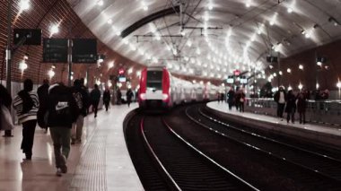 Monte Carlo, Monako - 4 Aralık 2024: Monako tren istasyonunda parlak ışıklarla hareket eden insanlar ve trenler